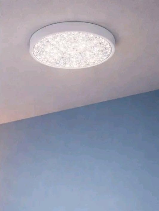 مصباح كريستالي دائري مضاء ومثبت في سقف أبيض بجوار حائط أزرق
