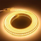 شريط إضاءة LED ملفوف ومضاء بلون أبيض دافئ، مع ظهور وصلة الطاقة على خلفية داكنة
